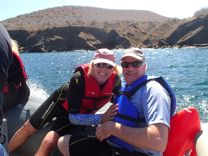 older man and woman hugging while on boat overlooking water and mountains