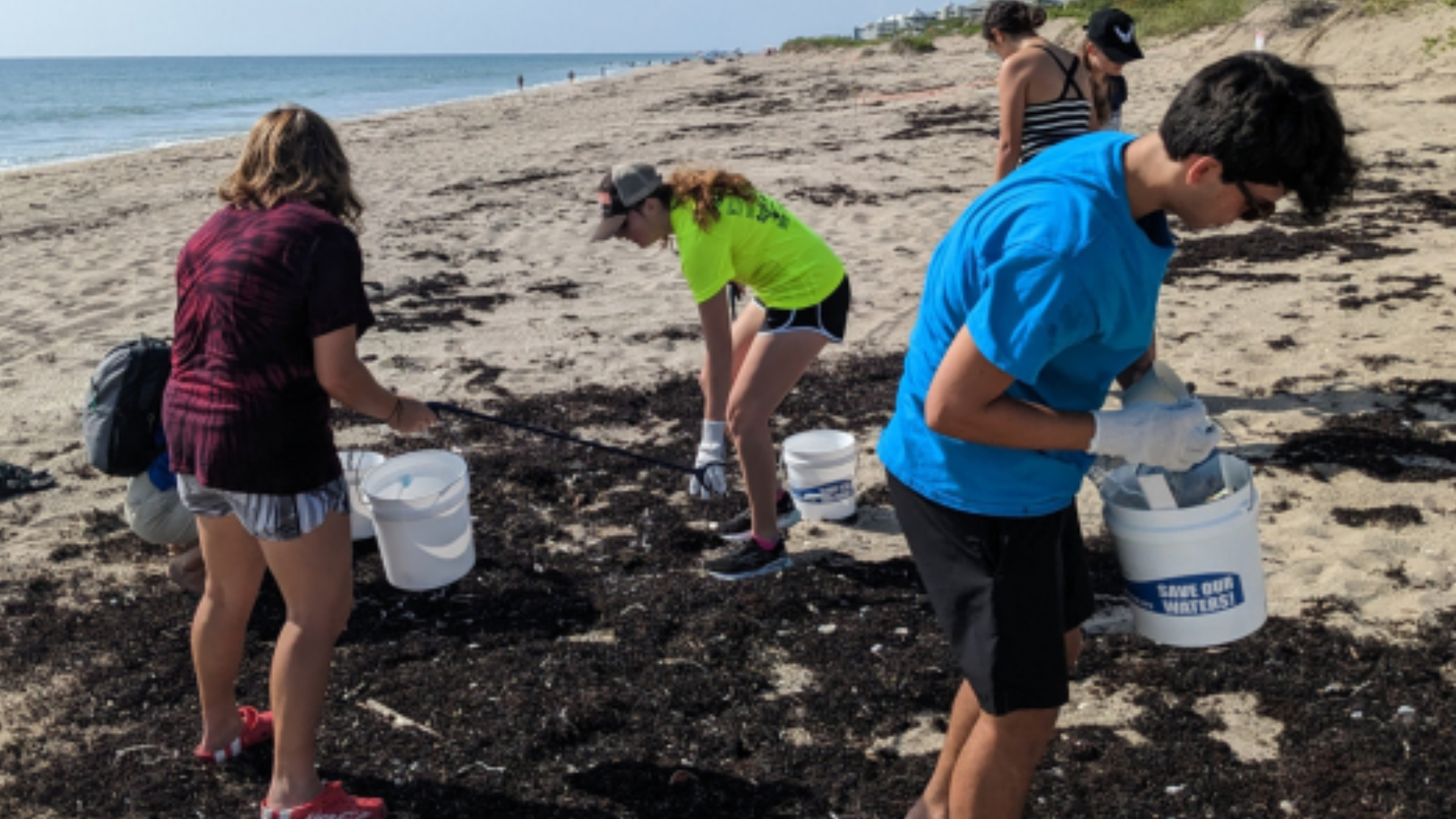 kids on beach picking up trash